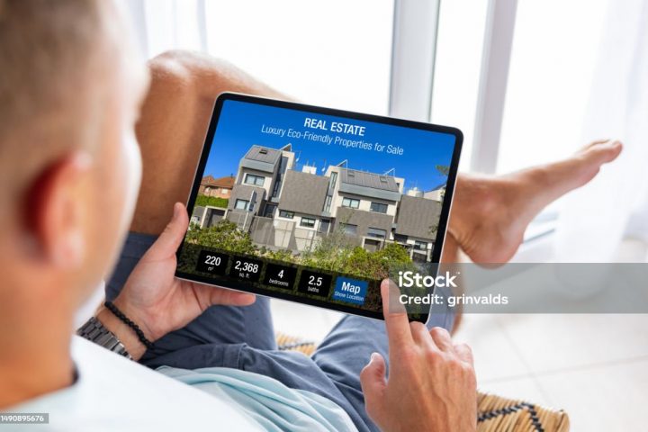 Man looking at real estate website on tablet computer, searching for a new house to buy